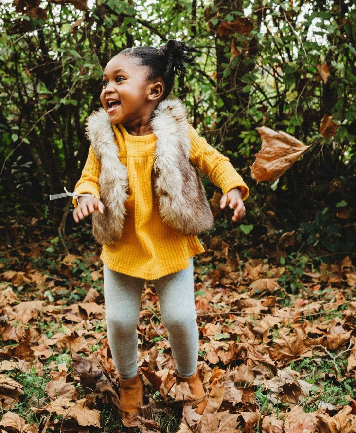 toddler girl playing in leaves